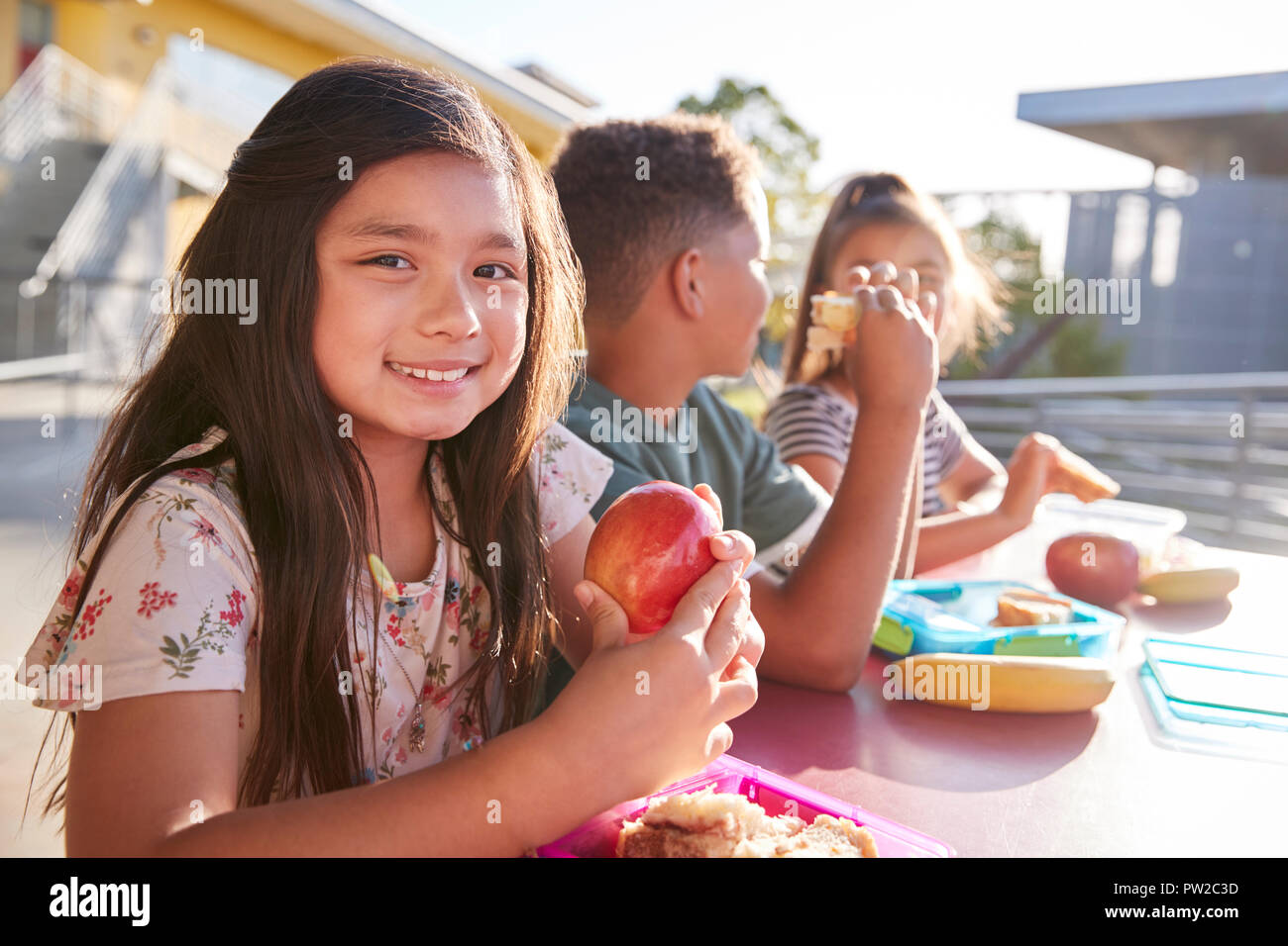 Girl at elementary school lunch table smiling to camera Stock Photo