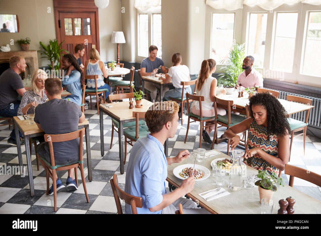Customers Enjoying Meals In Busy Restaurant Stock Photo