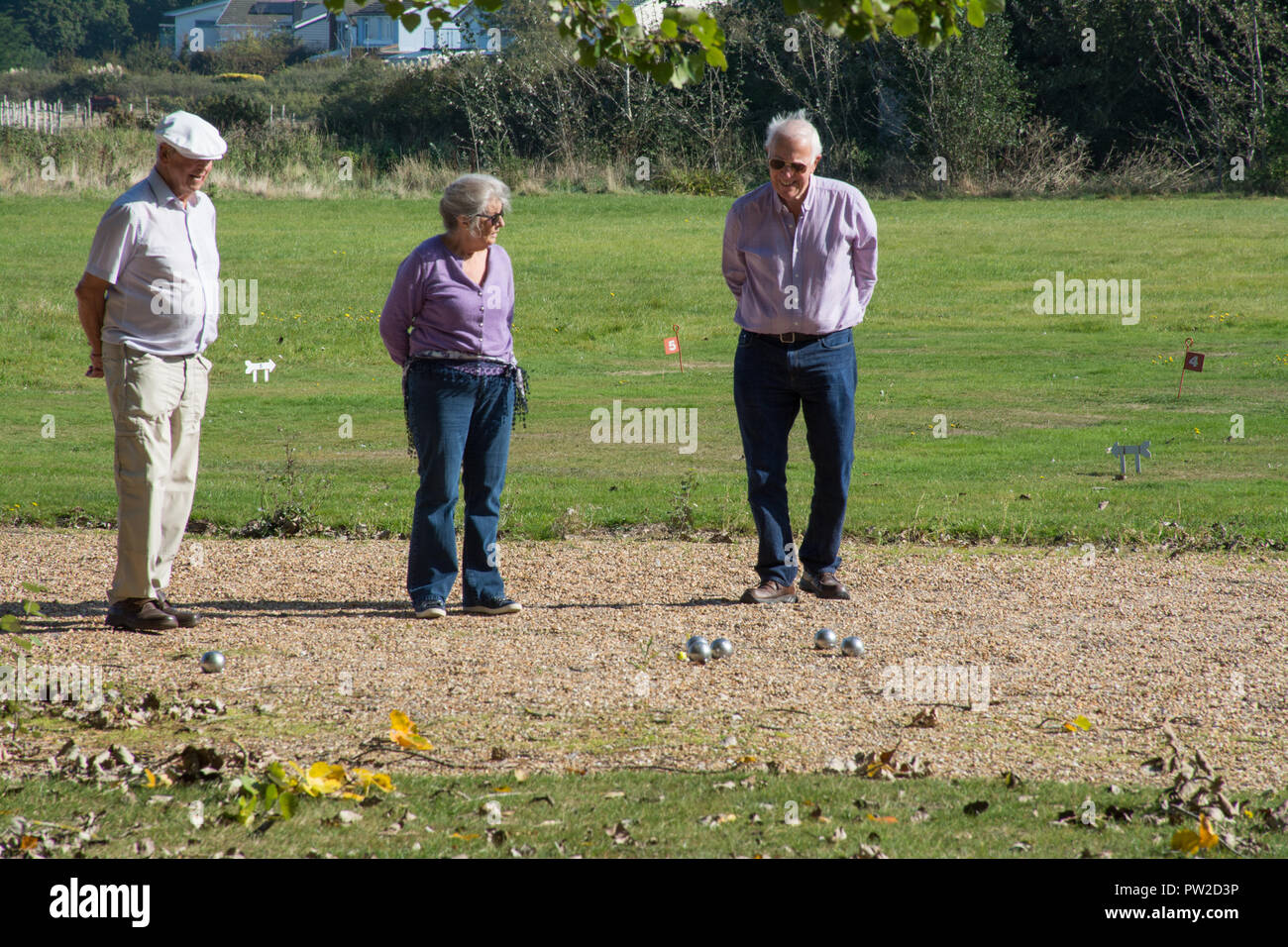 Three older people playing boules outdoors on a sunny day Stock Photo