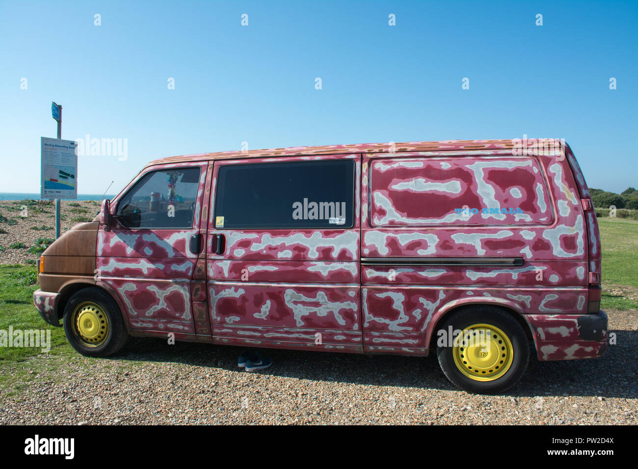 Colourful van painted red and white with bright yellow wheels parked close to the beach in Hampshire, UK Stock Photo