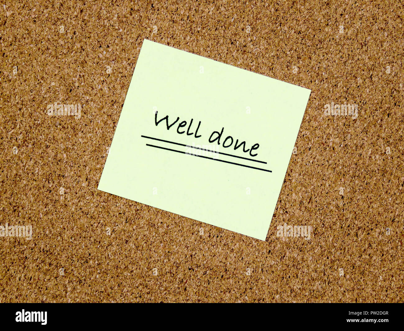 A yellow sticky note with well done written on it on a cork board background Stock Photo