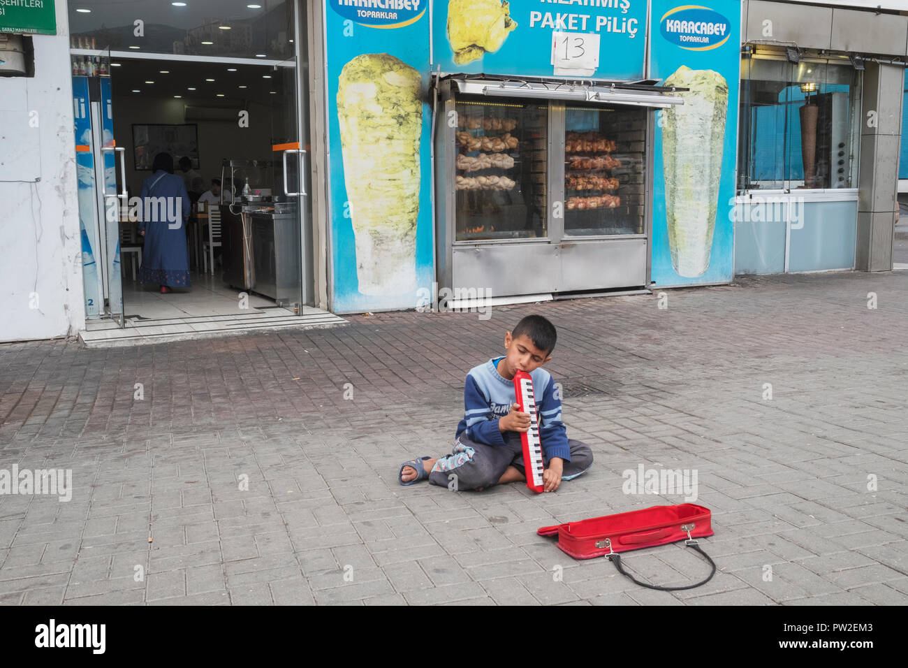 A Syrian child refugee plays for alms along a street in Bursa, Turkey Stock Photo