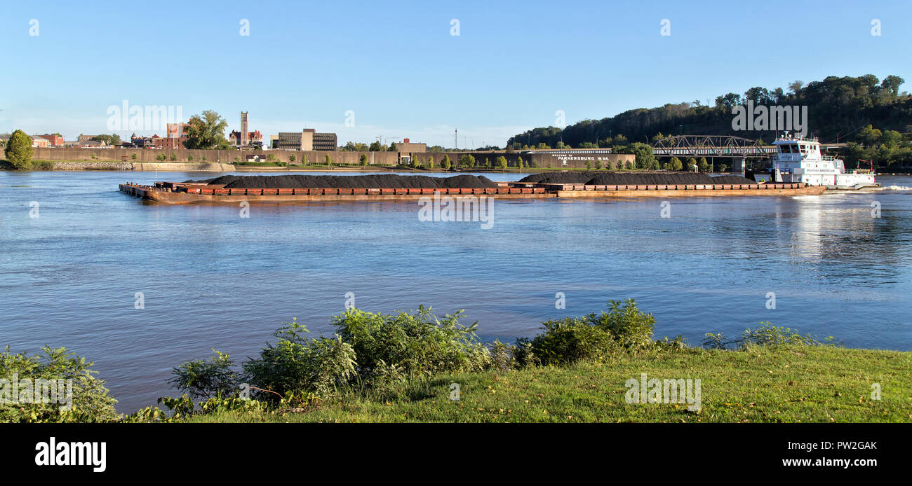 Tugboat pushing coal loaded barges, Ohio River, Parkersburg in the background. Stock Photo