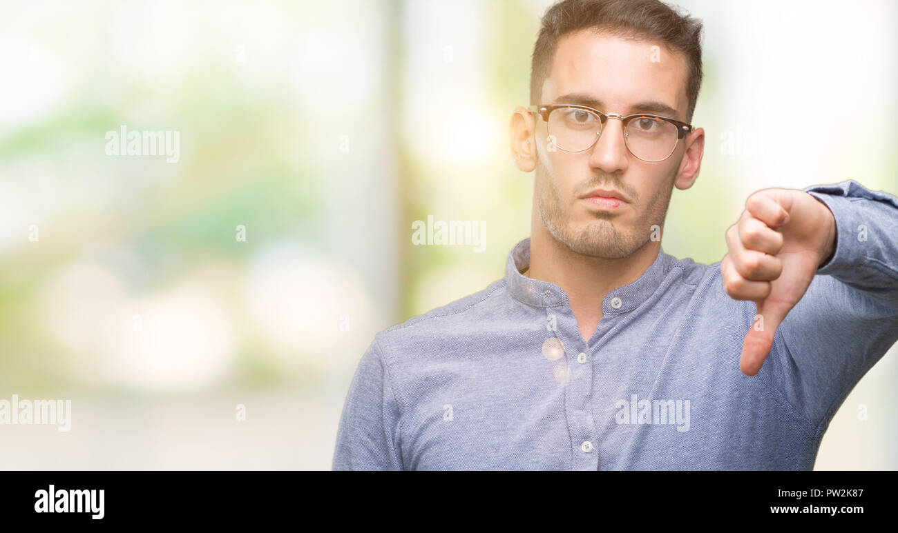 Handsome young elegant man wearing glasses looking unhappy and angry ...