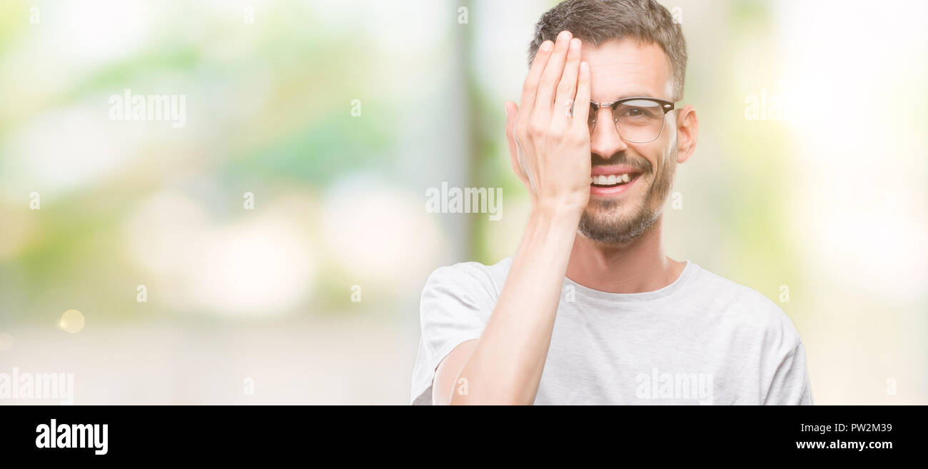 Young tattooed adult man covering one eye with hand with confident ...