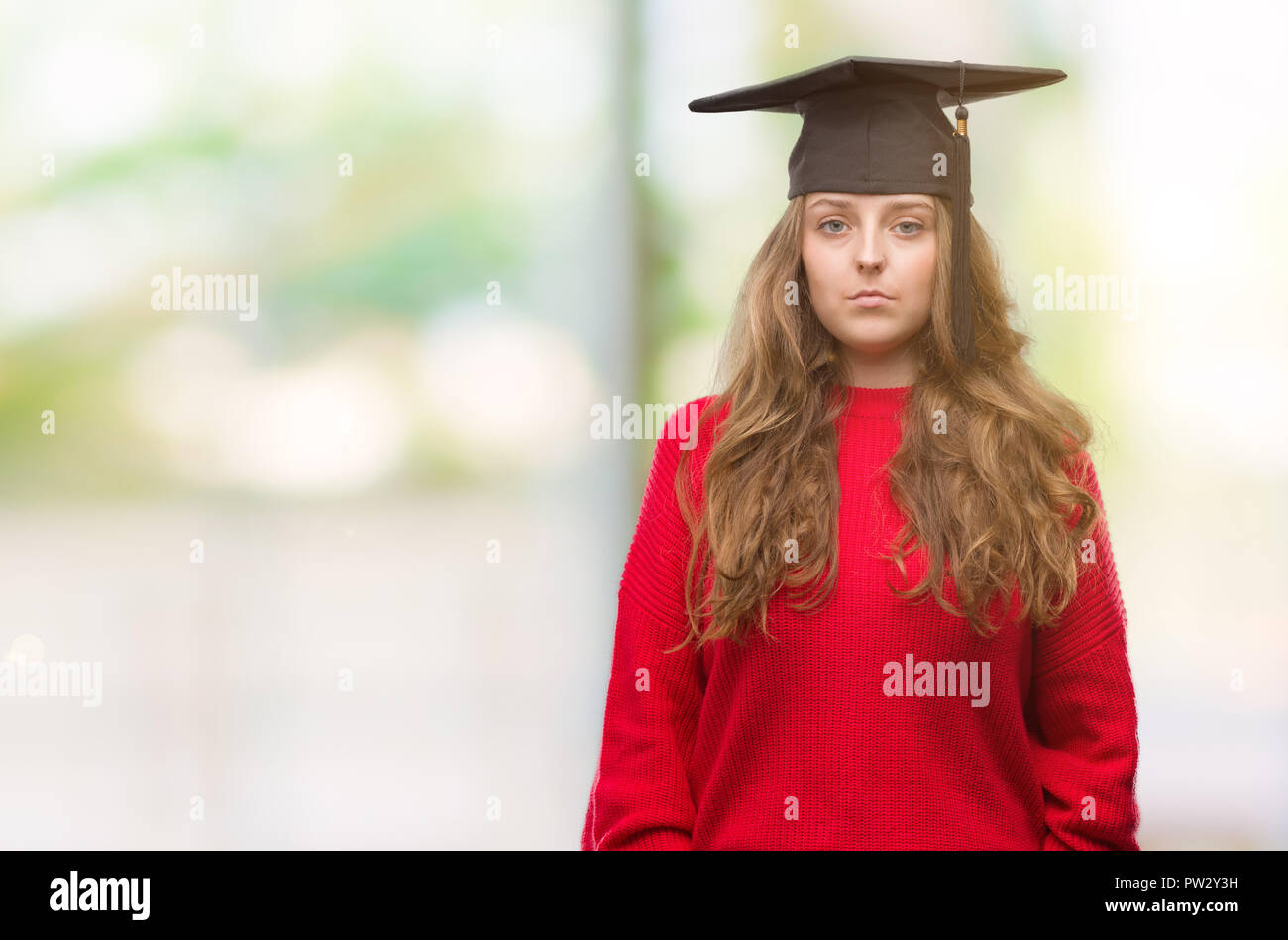 Young blonde woman wearing graduation cap with a confident expression ...