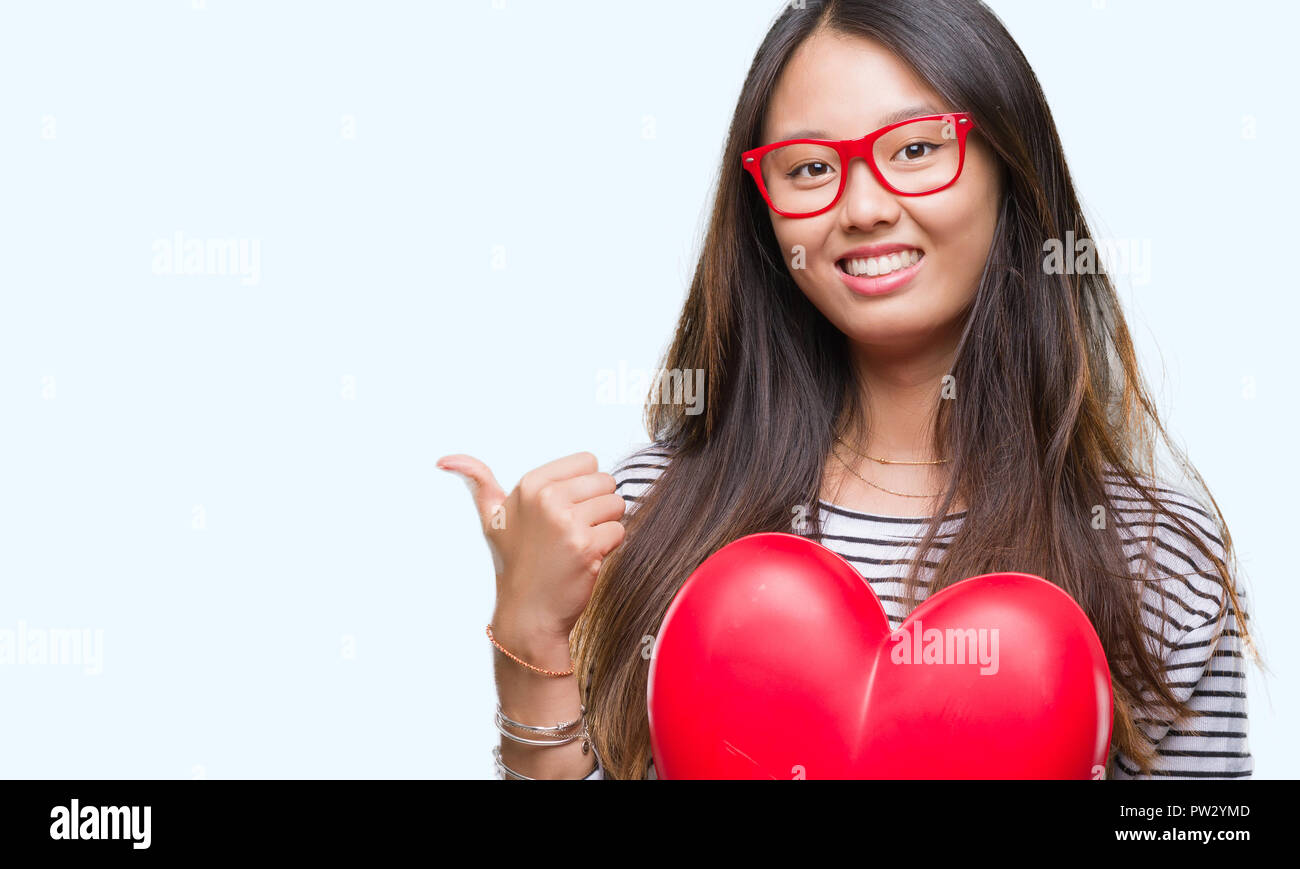 Young asian woman in love holding read heart over isolated background ...