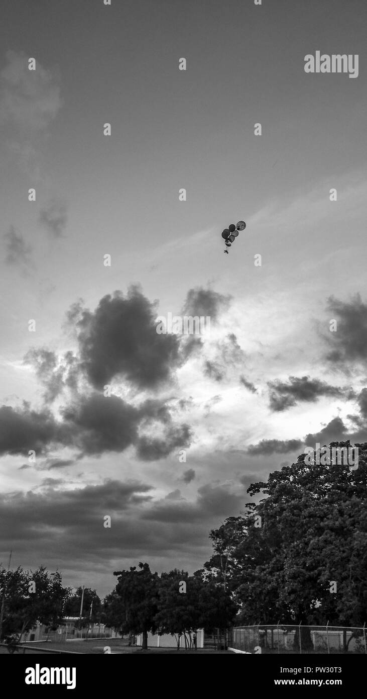 Globe with helium floating towards the sky in black and white Stock Photo