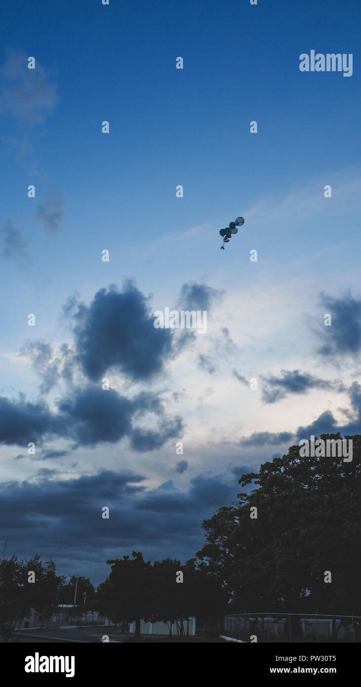 Globe with helium floating towards the sky in black and white Stock Photo