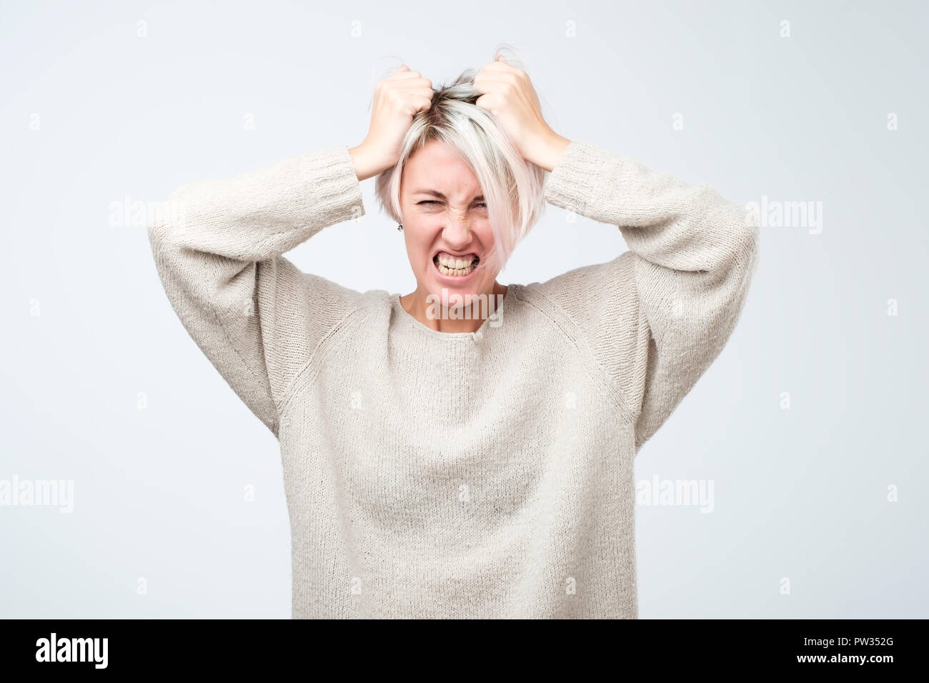 Young Female With Short Dyed Hair In White Sweater Stock Photo