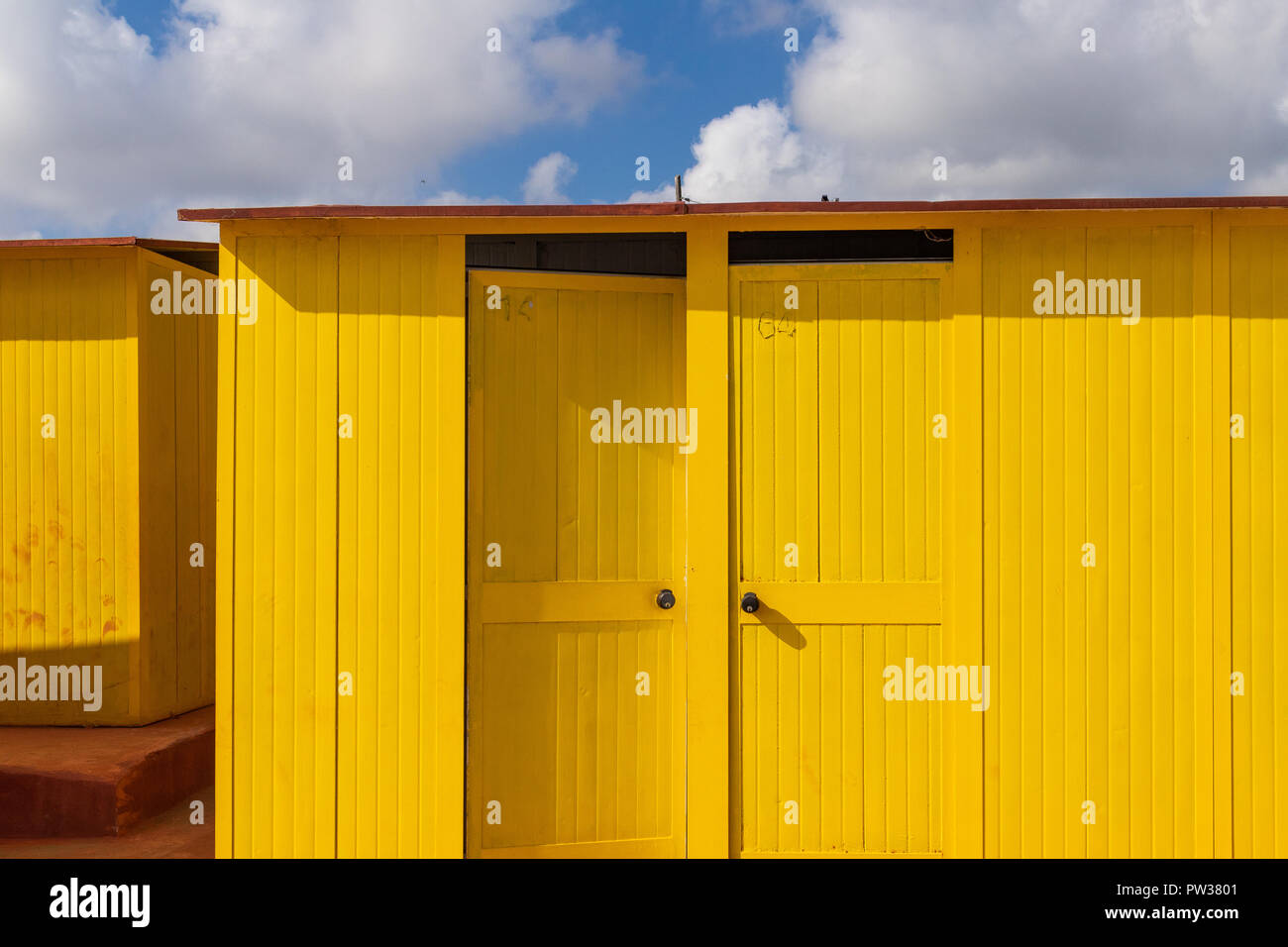 Beautiful yellow Bathing houses on the sandy beach. Empty shelters on a sunny but moody day. Seaside architecture, colored paint, maze-like labyrint. Stock Photo