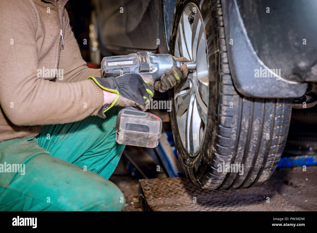 Seasonal tyre replacement. Auto mechanic changing car wheel. Stock Photo