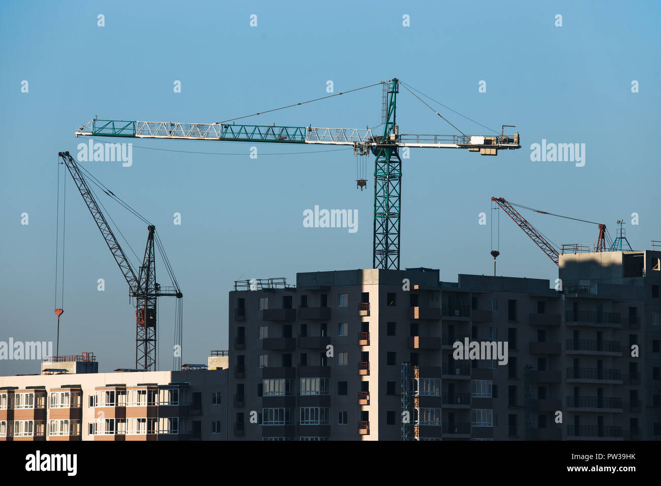 Construction of a residential high-rise building. Photo of a construction crane installing floor decks. Stock Photo