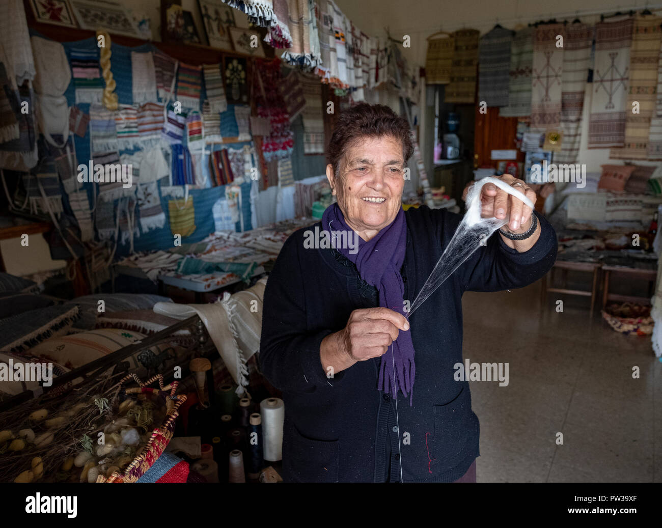 A woman holding cotton and explaining weaving methods at a Museum in Fyti village, Cyprus. Stock Photo
