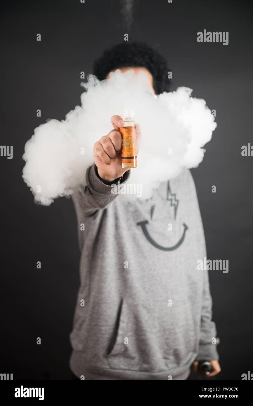 Vape concept. Smoke clouds and vape liquid bottles on dark background. Useful as background or vape advertisement or vape background. Stock Photo
