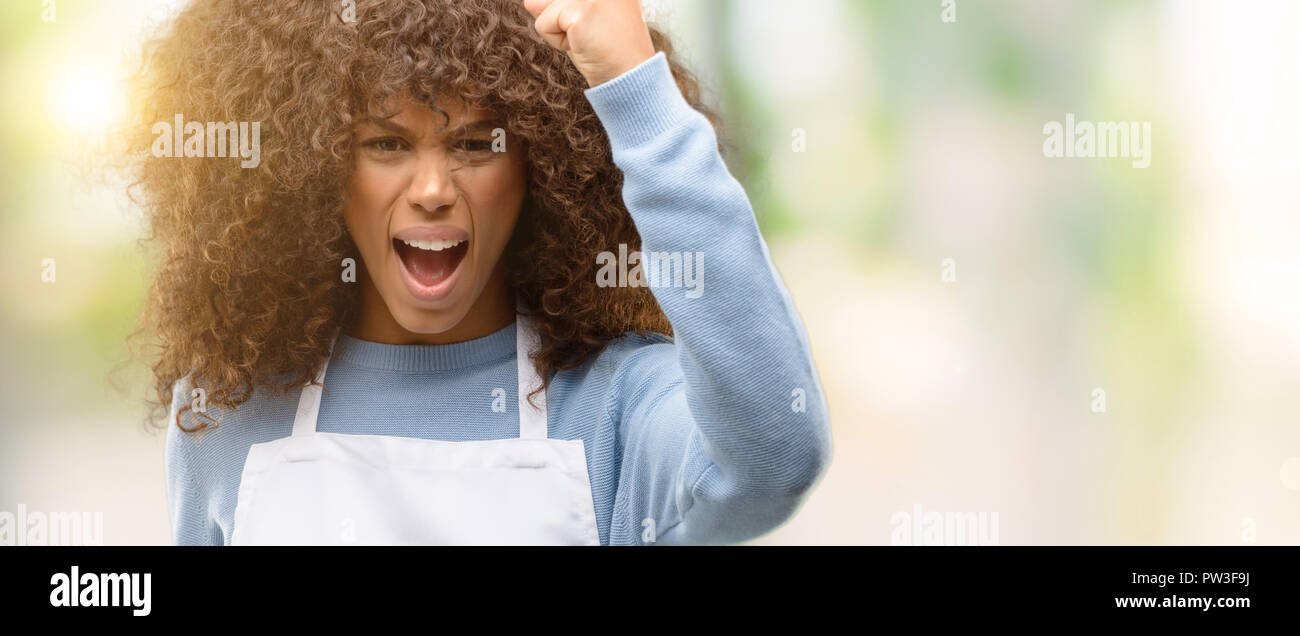 African american shop owner woman wearing an apron irritated and angry ...