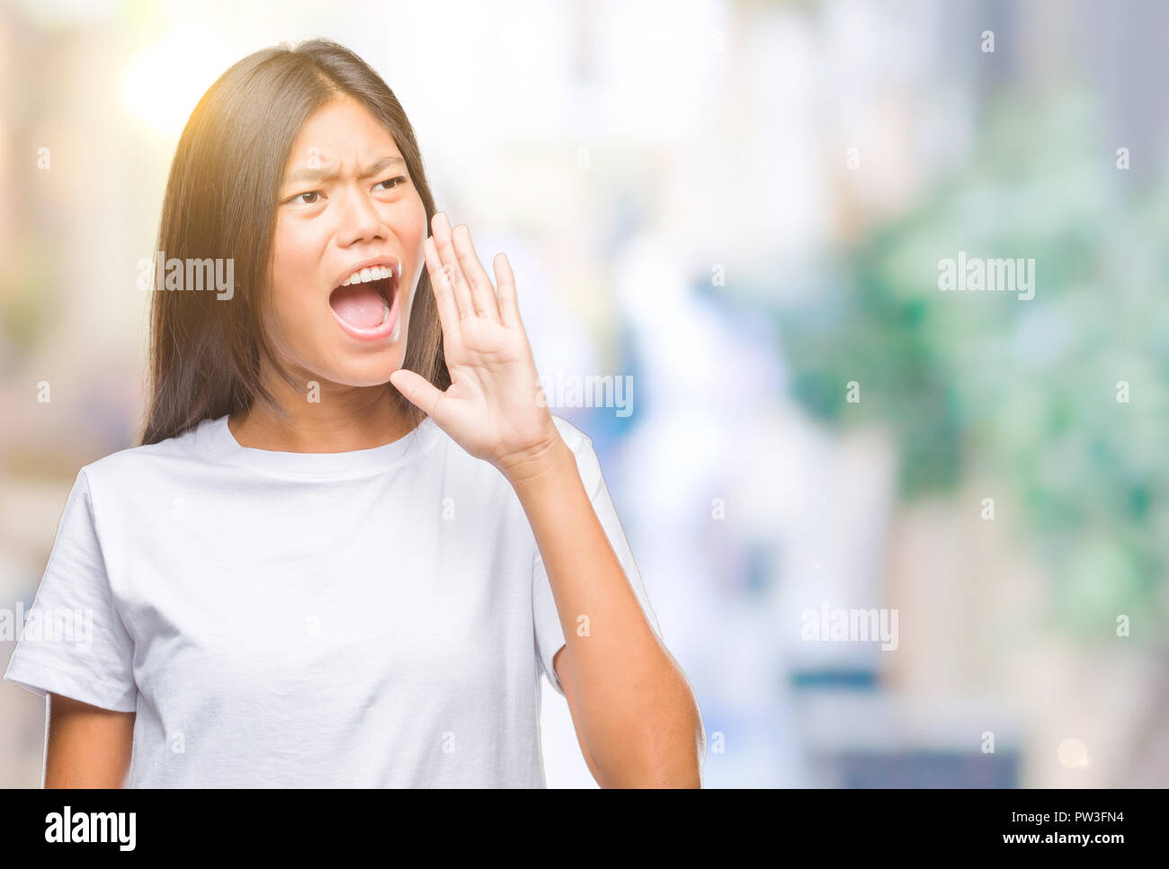 Young asian woman over isolated background shouting and screaming loud ...