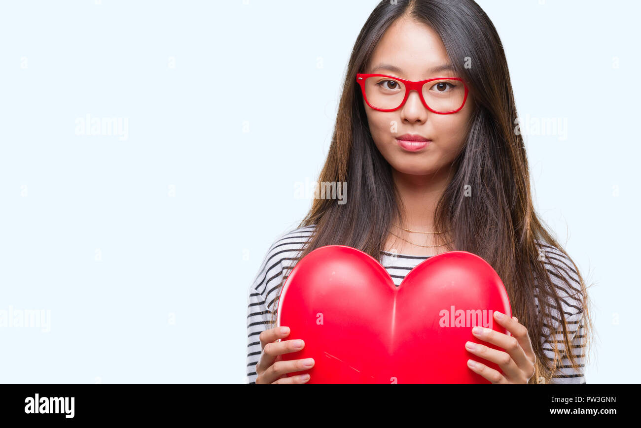 Young asian woman in love holding read heart over isolated background ...
