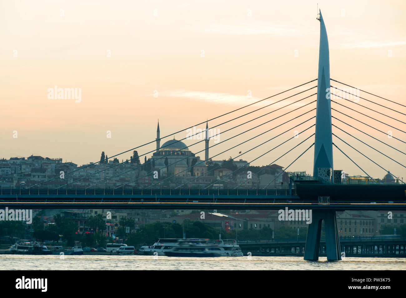 The Haliç Golden Horn Metro Bridge with mosque in background at sunset, Istanbul, Turkey Stock Photo