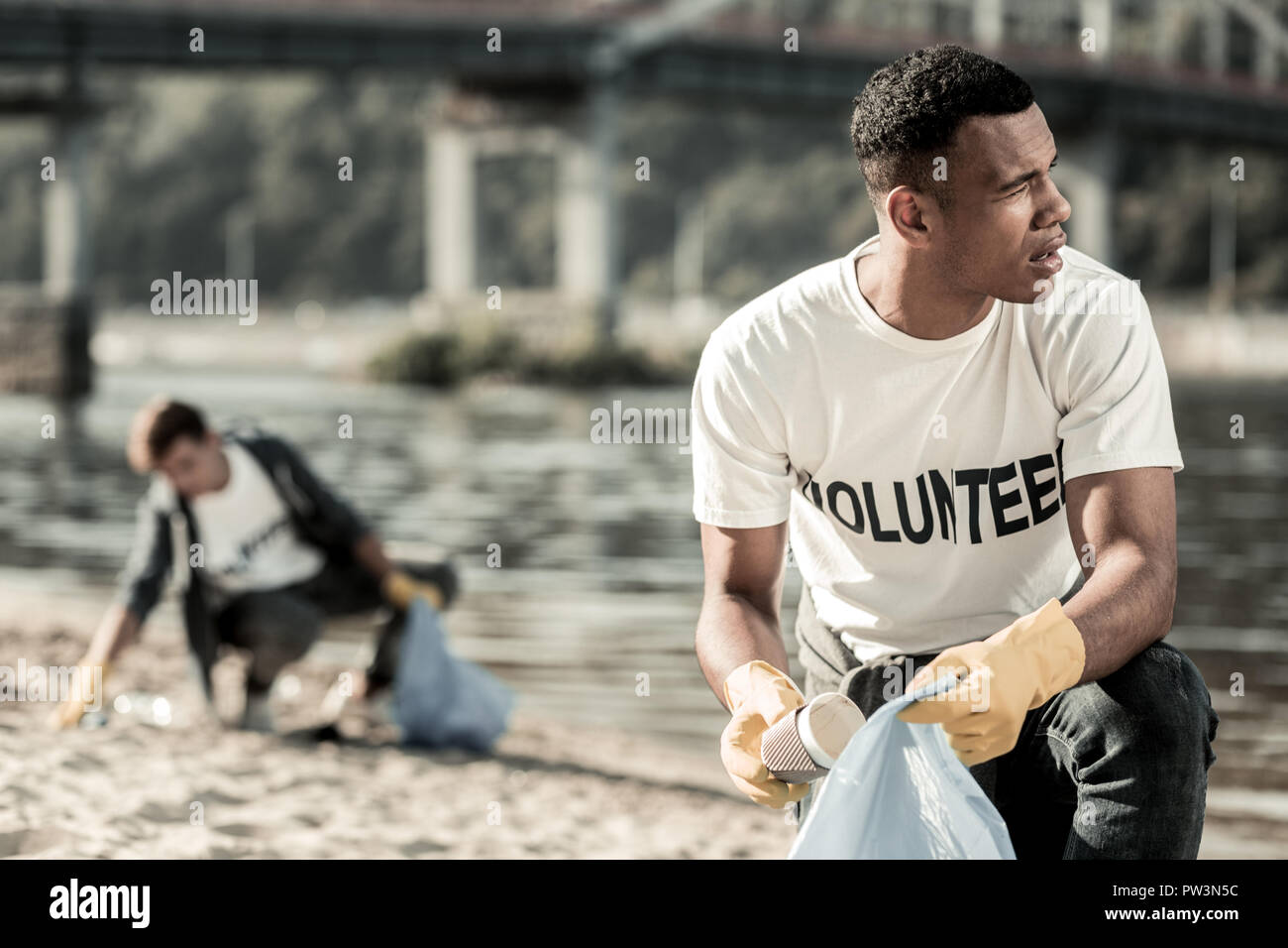 Handsome dark-haired student being socially active while cleaning the beach Stock Photo