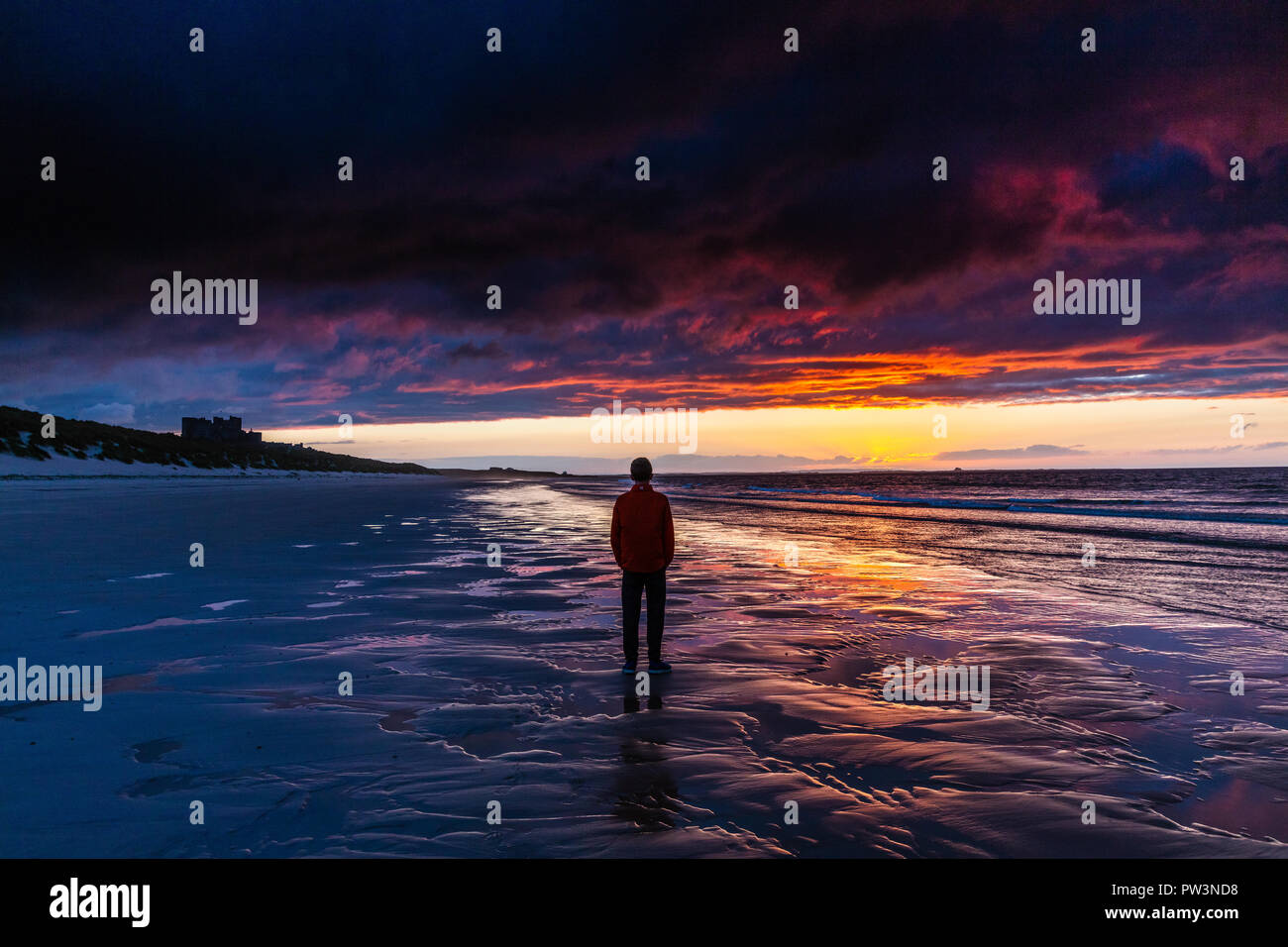 watching the sunset on the beach at Bamburgh, Northumberland, UK Stock Photo