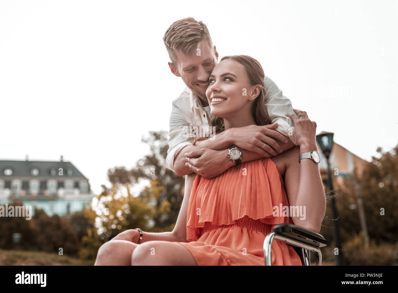 Disabled girl feeling happy while handsome man hugging her Stock Photo