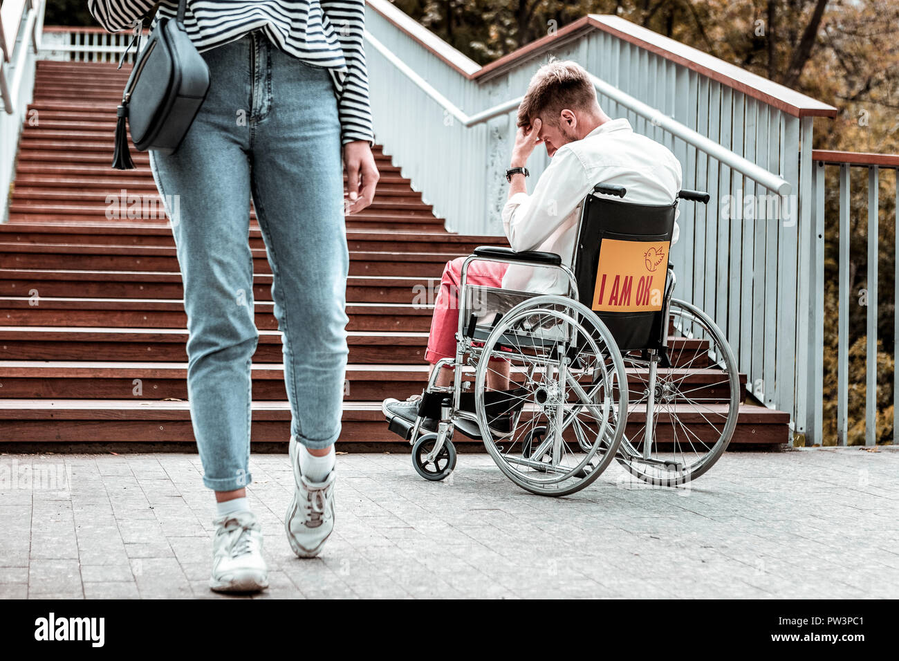 Young woman passing disabled man and not helping him Stock Photo