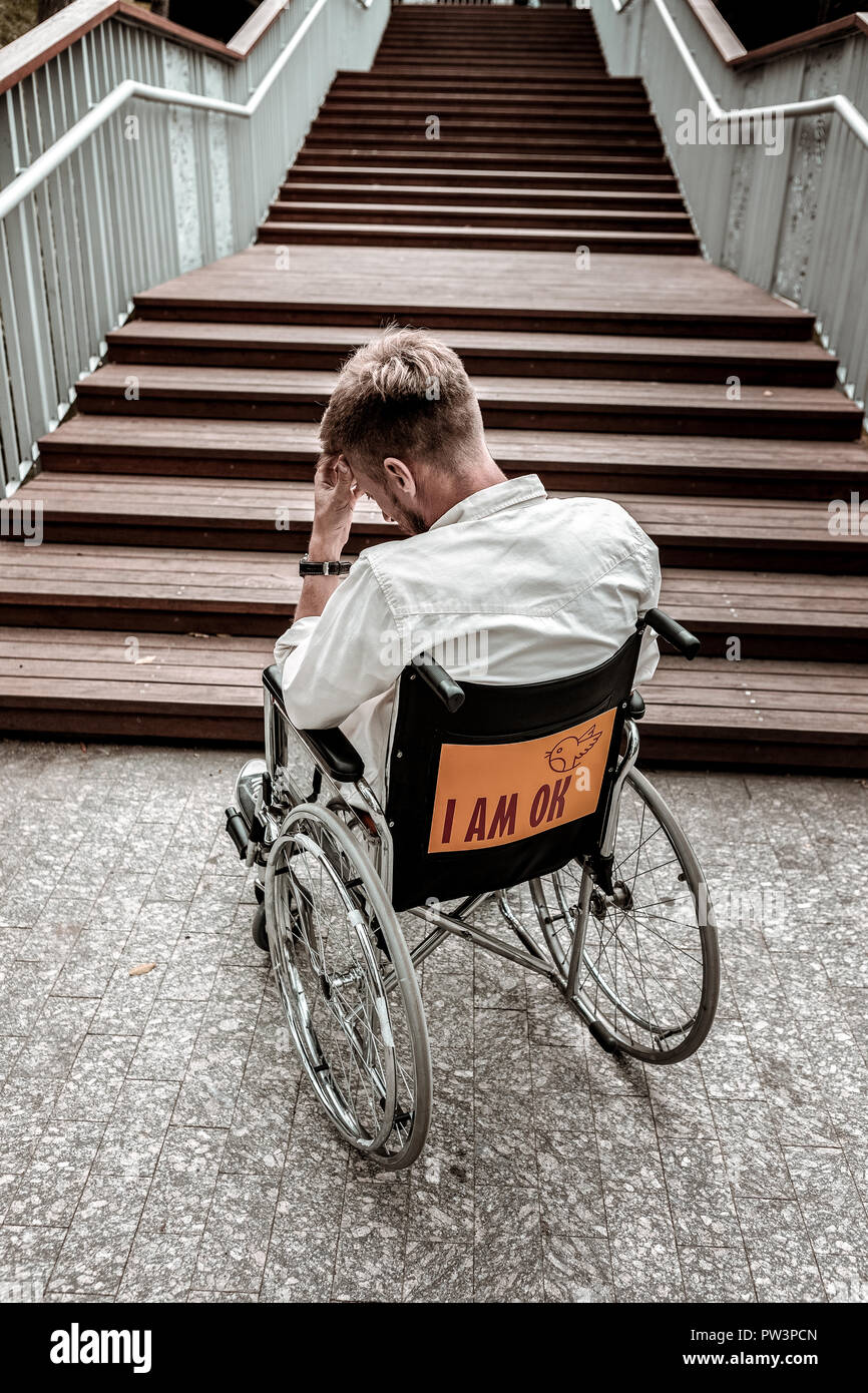 Unhappy disabled man sitting in wheelchair and facing a problem Stock Photo