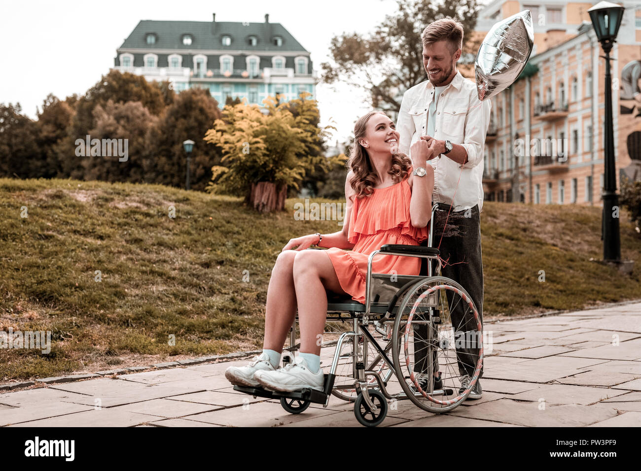 Girl in wheelchair looking happy while spending time with boyfriend Stock Photo