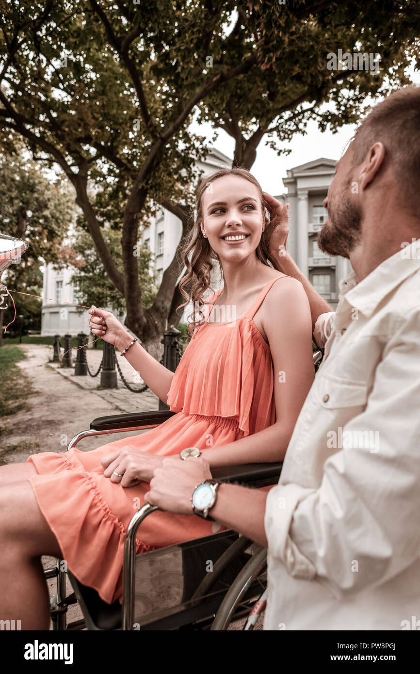 Disabled girl feeling happy while her boyfriend touching her hair Stock Photo