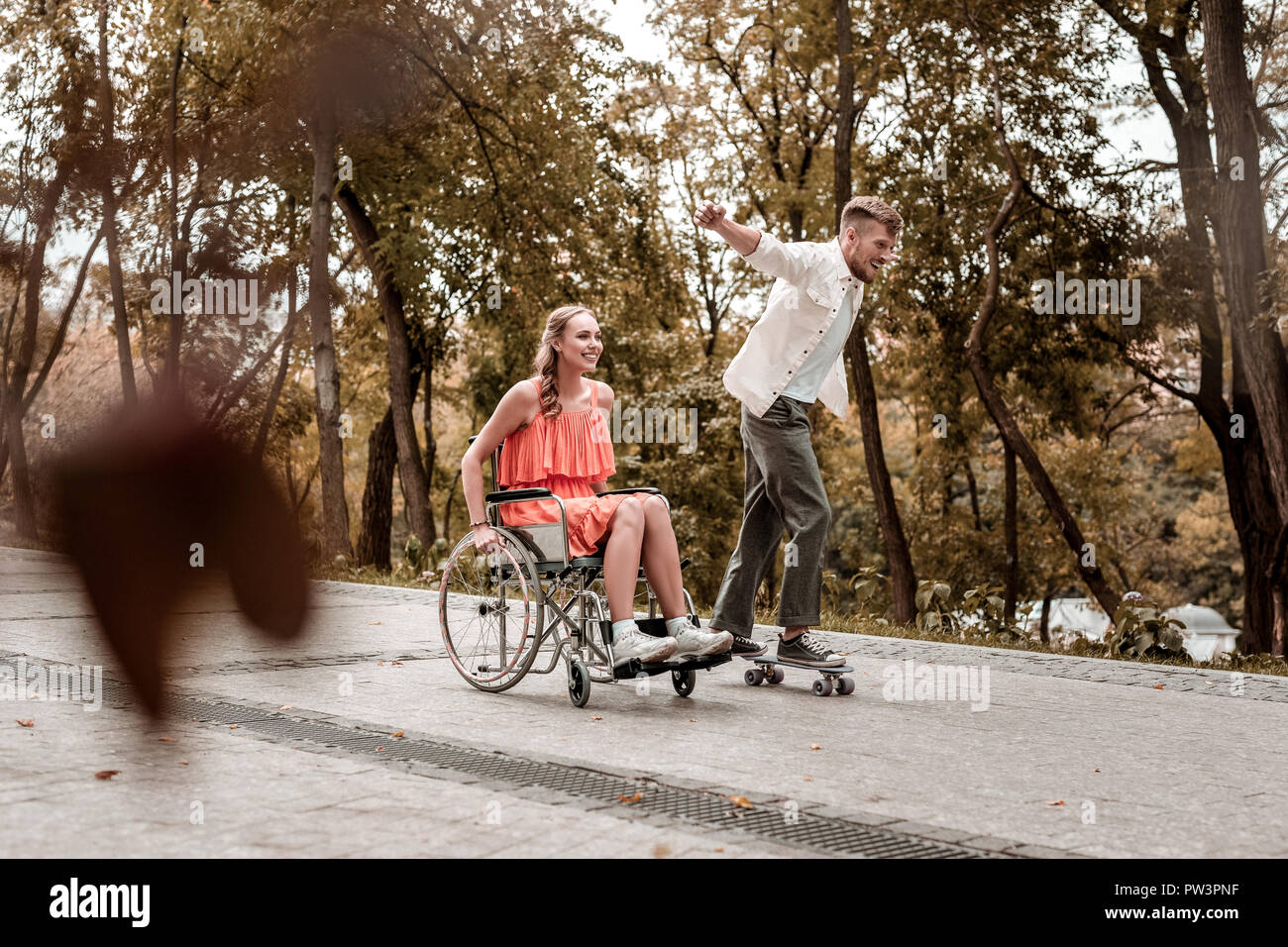 Happy man enjoying the speed of skateboard and his girlfriend smiling Stock Photo