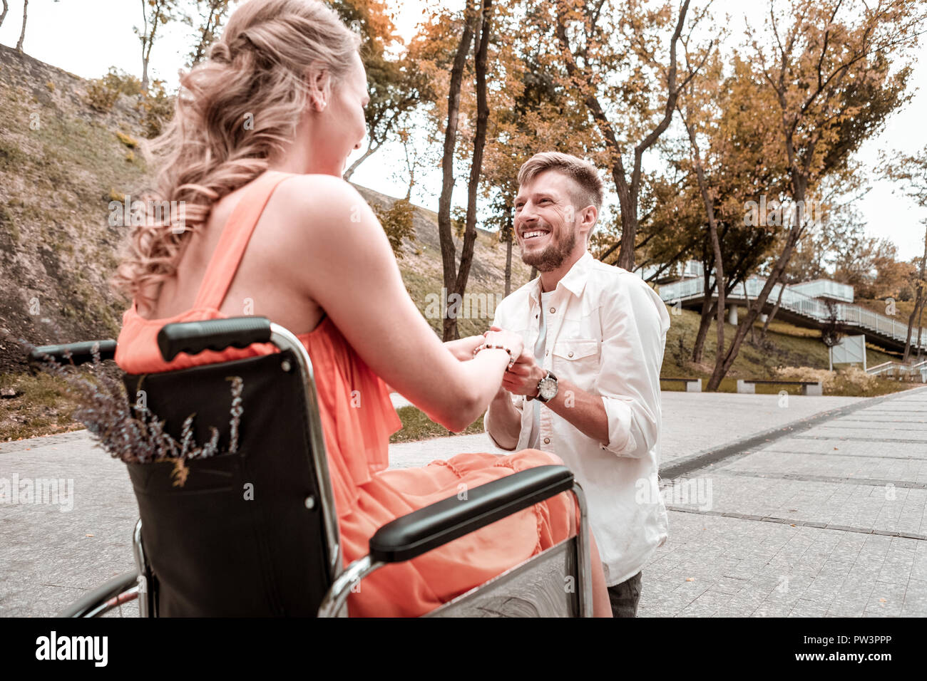 Happy man standing on one knee and making a proposal to his girlfriend Stock Photo