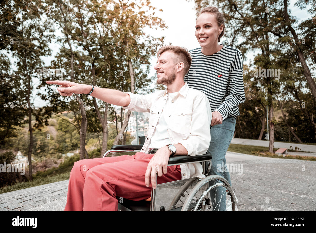 Disabled man feeling happy while showing the park to his pretty girlfriend Stock Photo