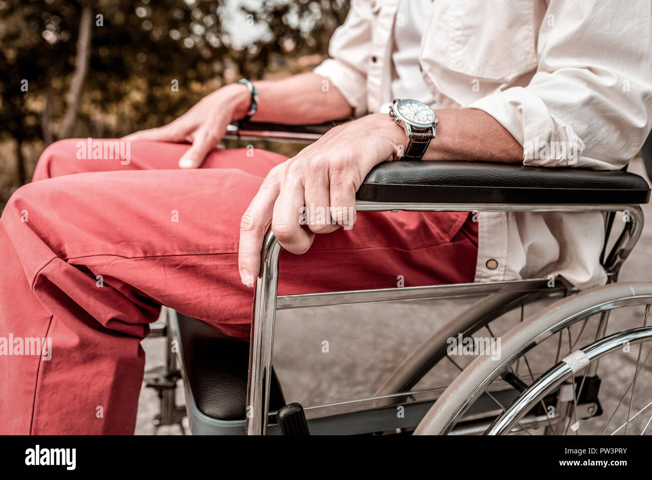 Close up of young man sitting in the wheelchair with his hands relaxed Stock Photo