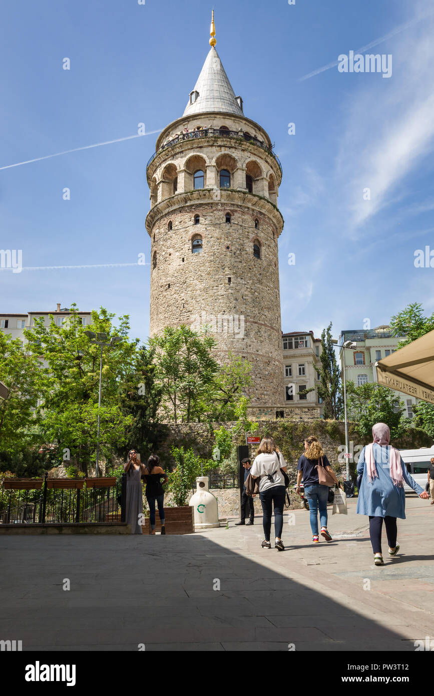 Galata tower dominates the skyline as people walk towards it on a sunny Spring day, Istanbul, Turkey Stock Photo