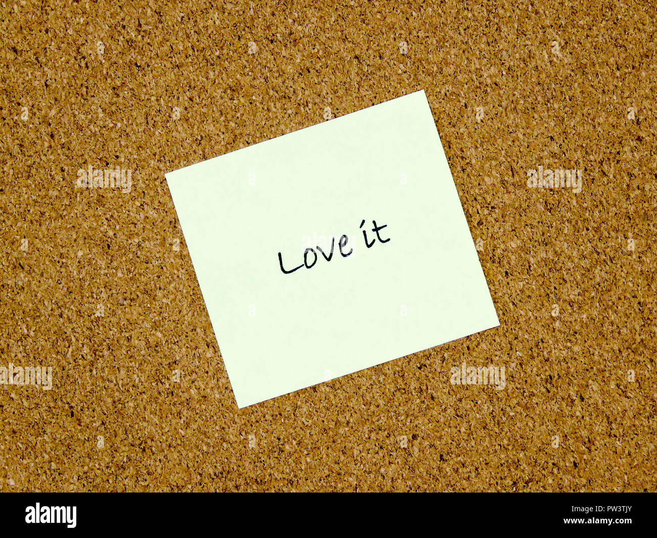 A yellow sticky note with love it written on it on a cork board background Stock Photo