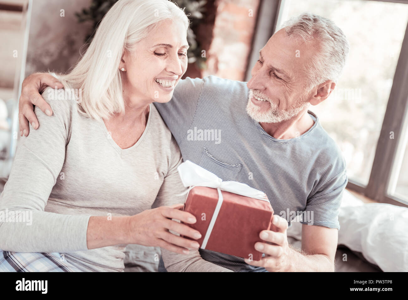 Cheerful husband presenting a gift to his wife Stock Photo Alamy
