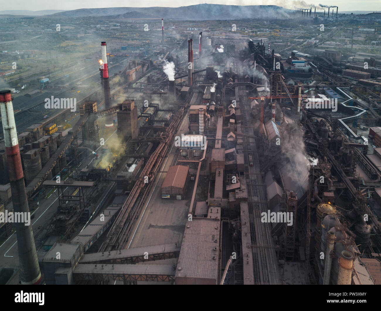 Panoramic view of heavy industry with detrimental impact on nature; CO2 emissions, toxic poisonous gases from chi mneys; rusty dirty pipelines and clo Stock Photo