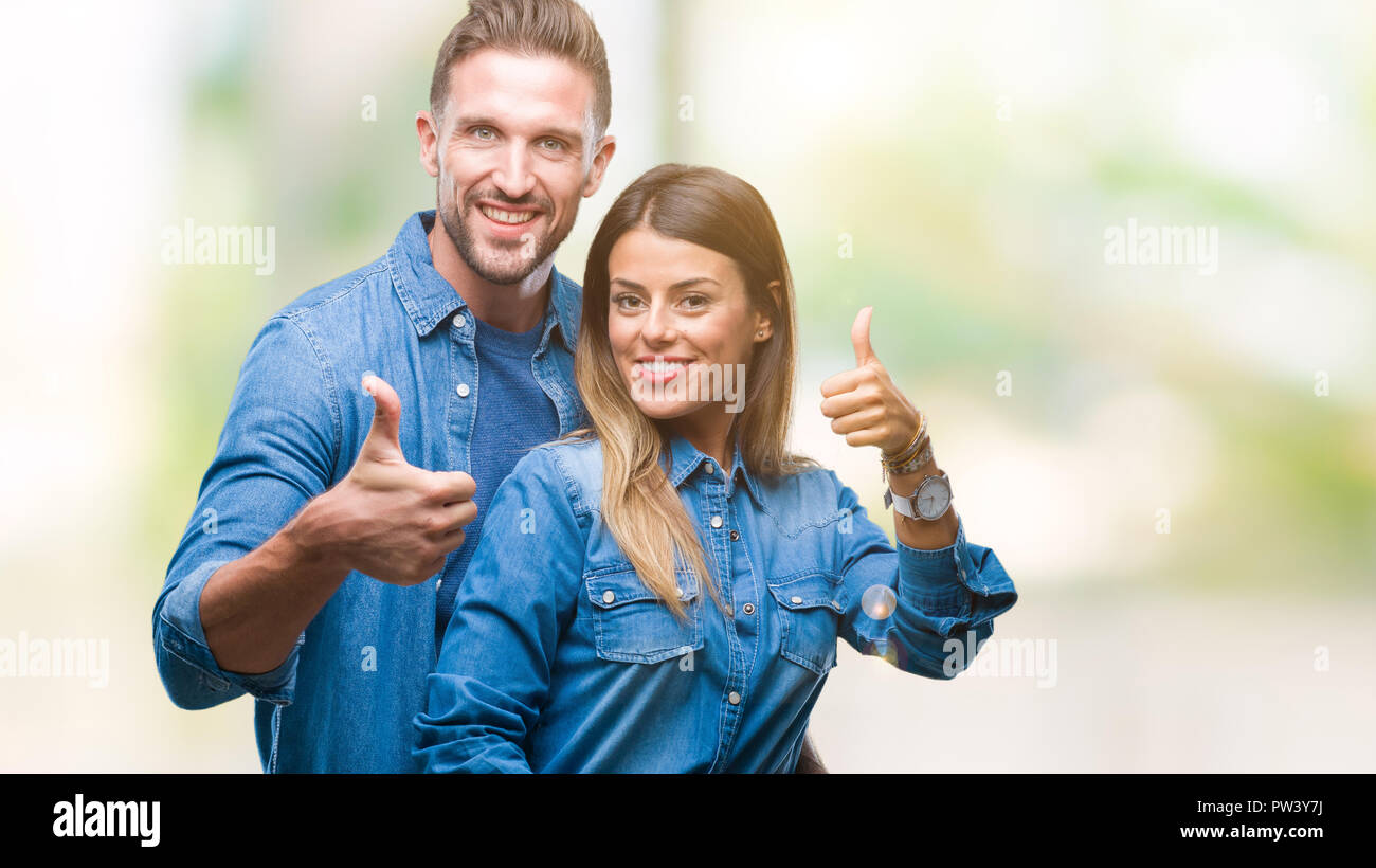 Young couple in love over isolated background doing happy thumbs up ...