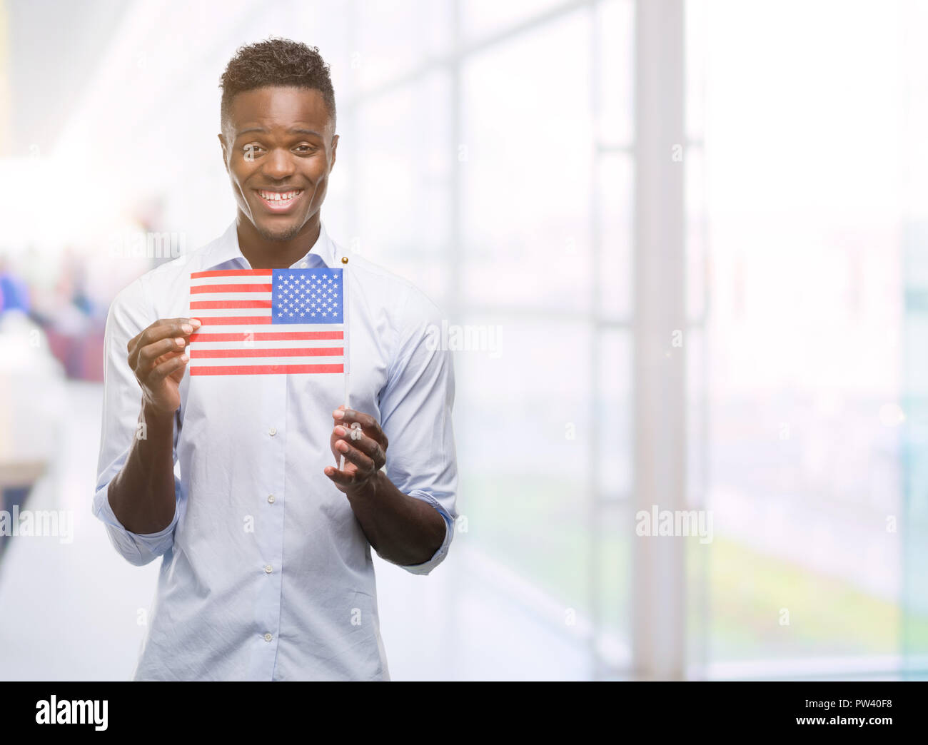 Young african american man holding USA flag with a happy face standing ...