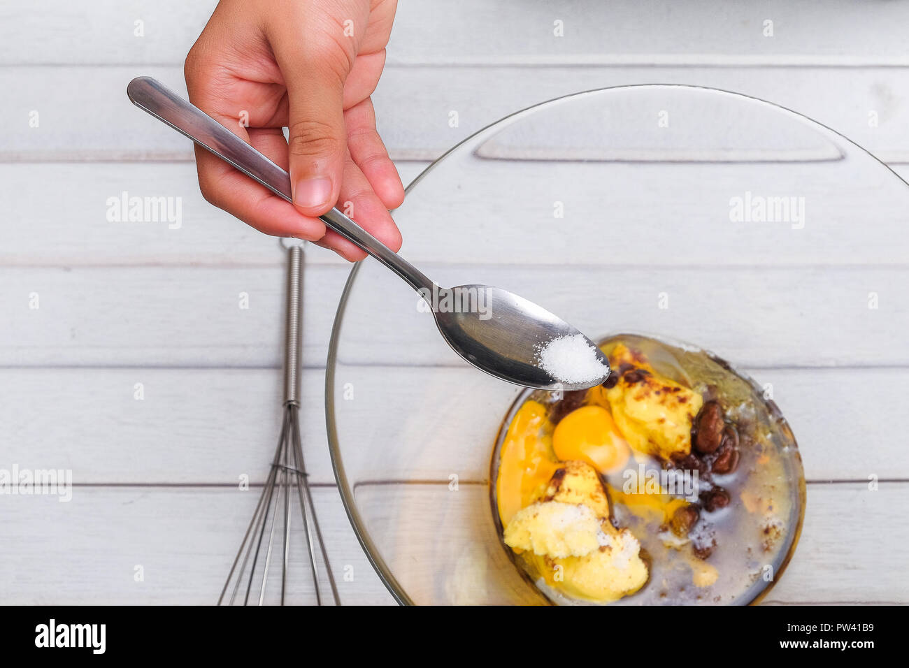 An Asian teen boy pouring a bit of salt into the bowl for making famous  amous. Food and cooking concept Stock Photo - Alamy