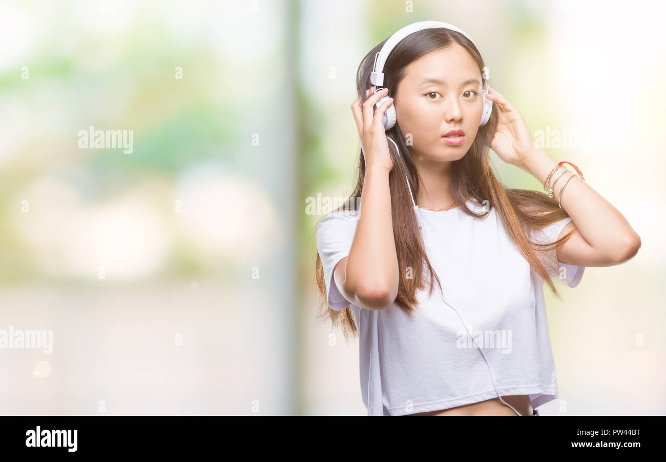 Young asian woman listening to music wearing headphones isolated ...