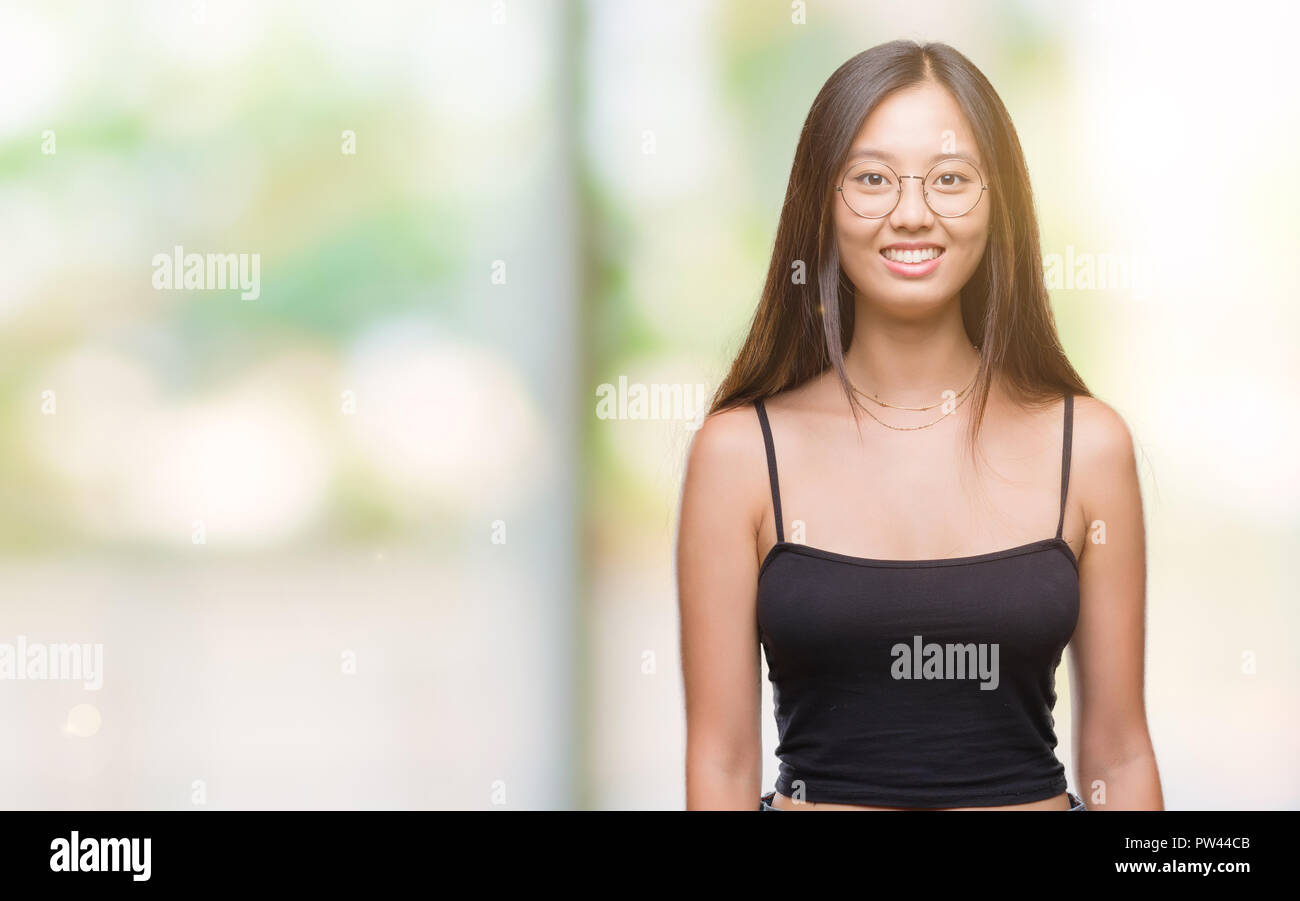 Young asian woman wearing glasses over isolated background with a happy ...