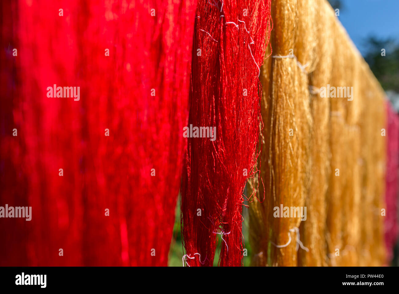 Colorful fabric hanging to dry after traditional dye processs in Luang Prabang, Laos. Silk production factory. Traditional manufacturing in Asia. Stock Photo