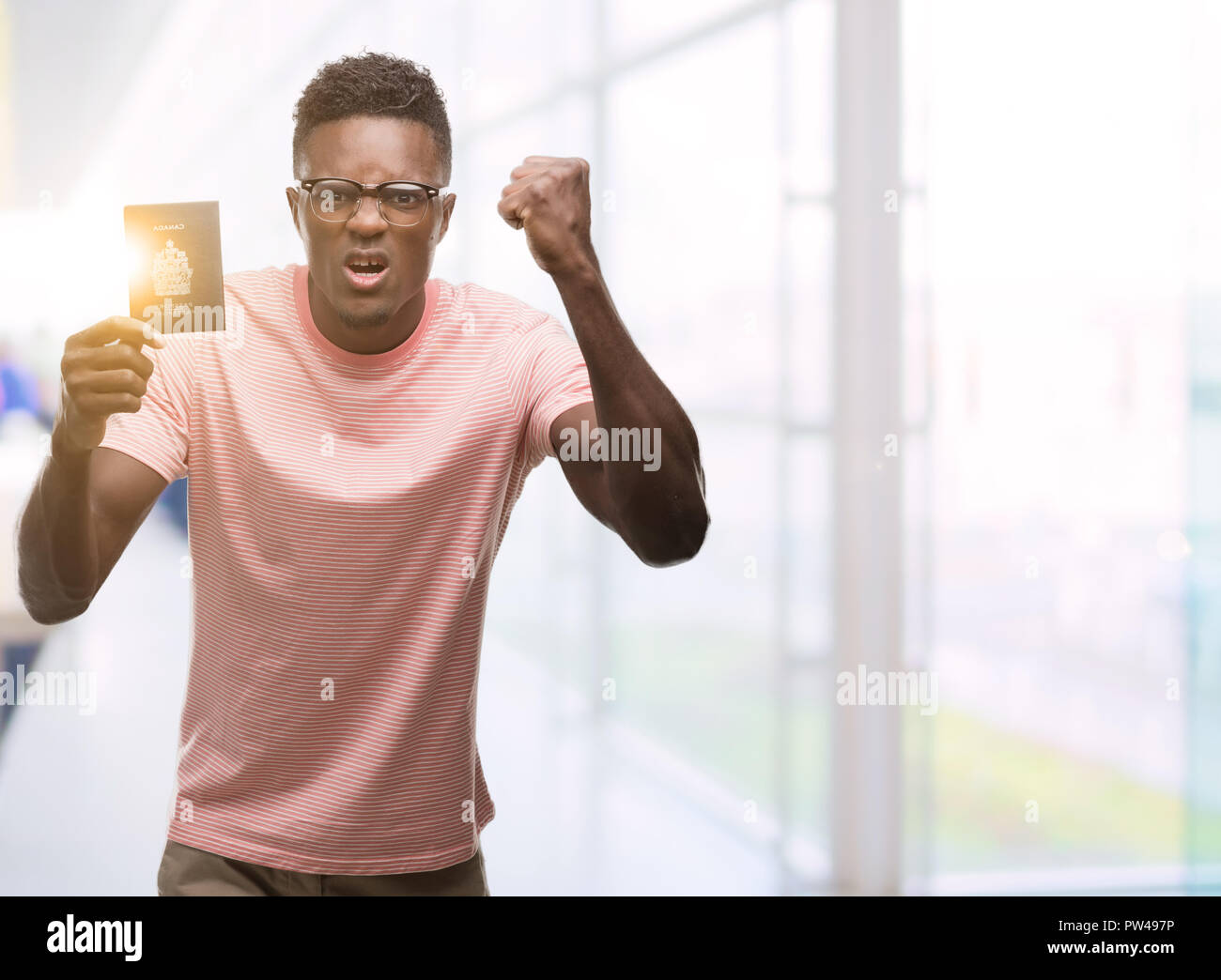 Young african american man holding canadian passport annoyed and ...