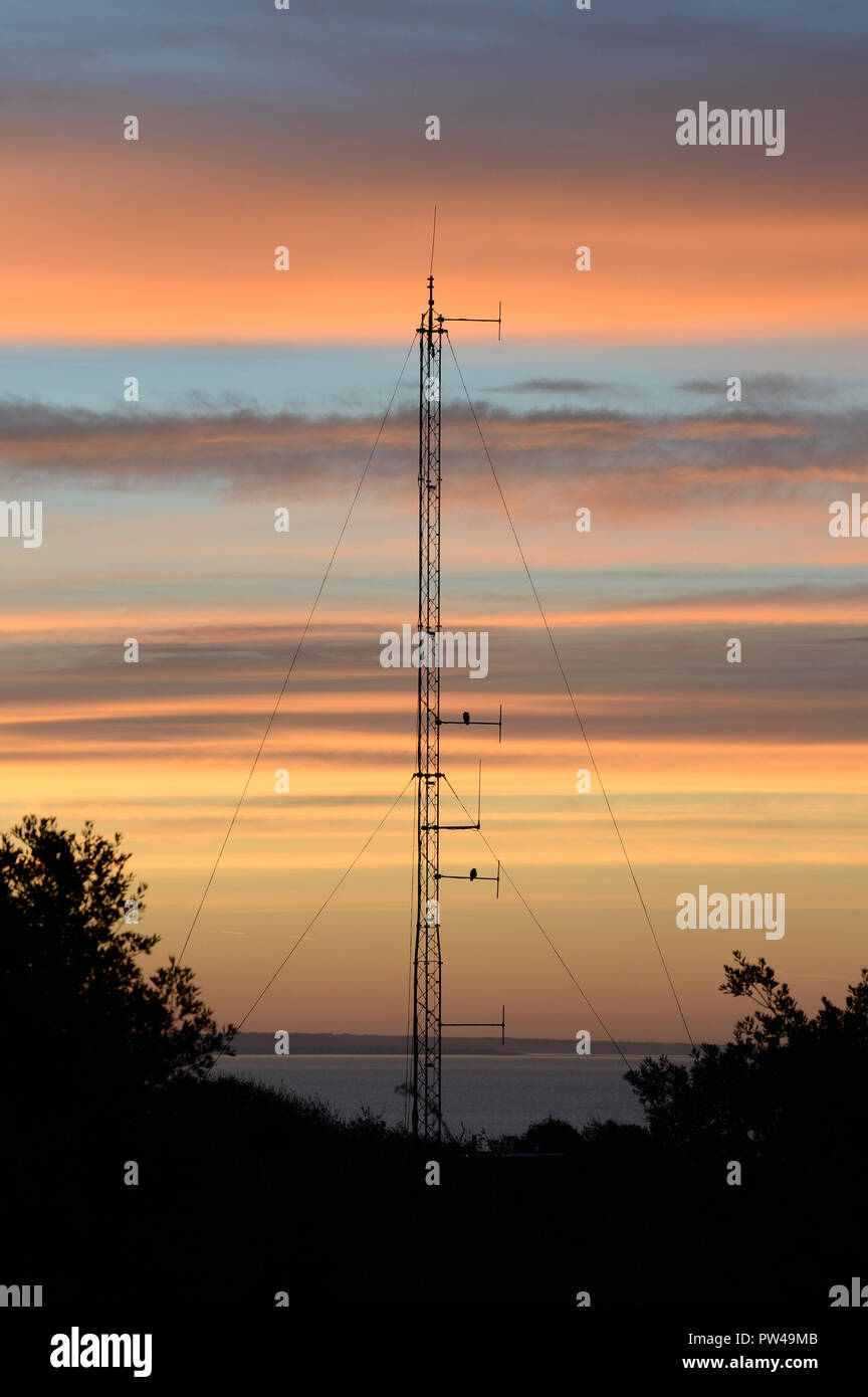 Radio mast silhouetted against the sunrise overlooking the Bristol Channel Stock Photo