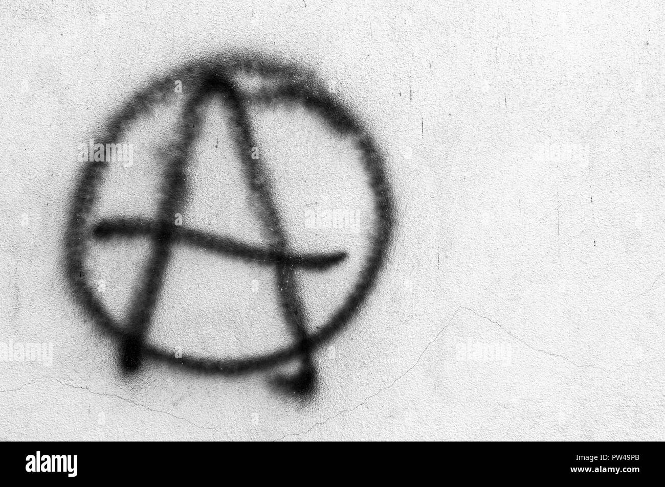 Symbol of Anarchy painted on a gray concrete wall. Ideal for concepts and backgrounds. Space for text. Stock Photo