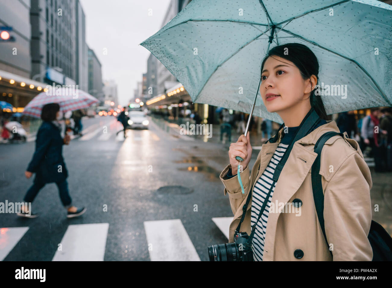 beautiful office lady crossing the road with a blue umbrella in the rainy day, it keeps the rains of her. Japanese photographer travel in Kyoto city i Stock Photo