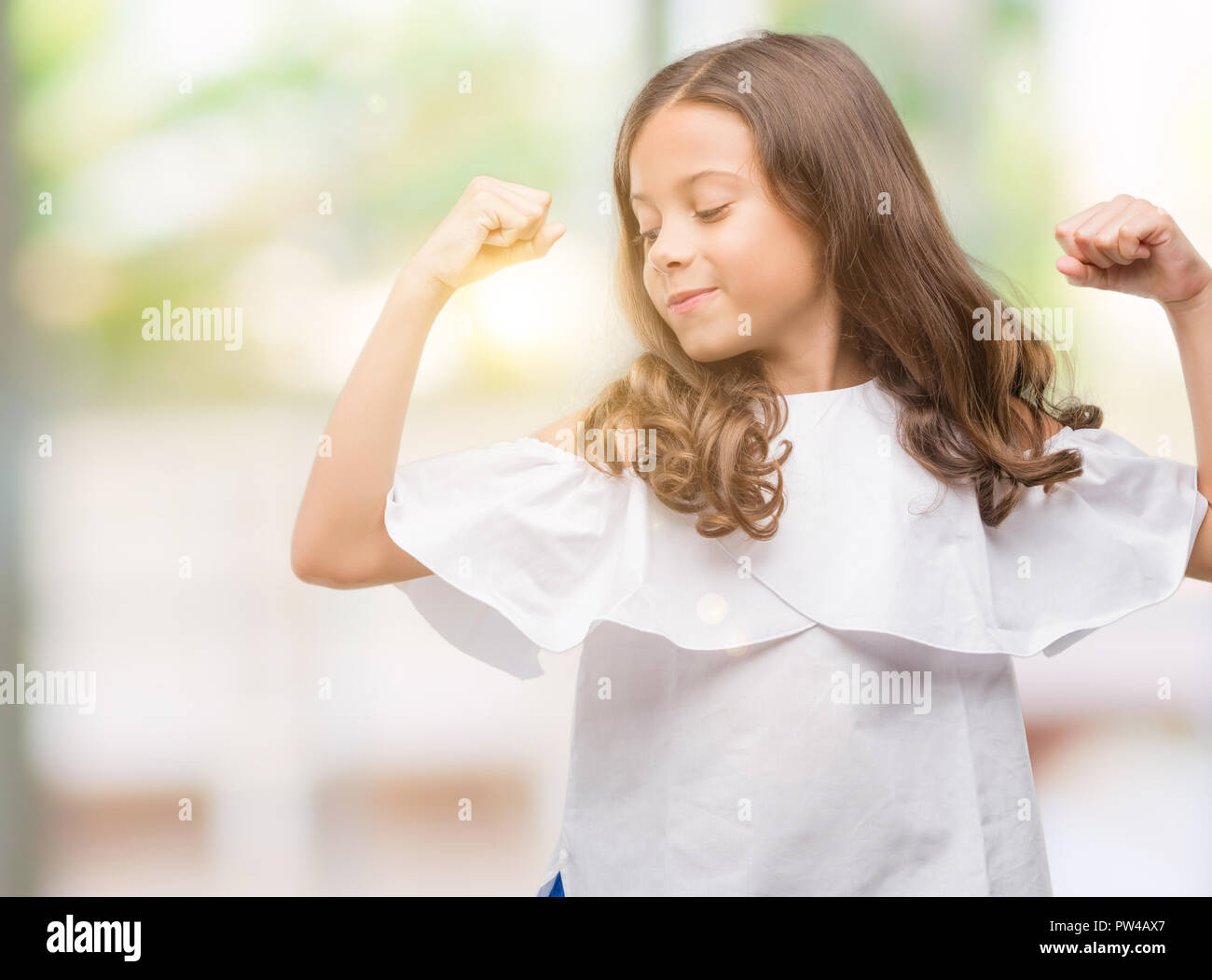 Brunette hispanic girl showing arms muscles smiling proud. Fitness concept. Stock Photo