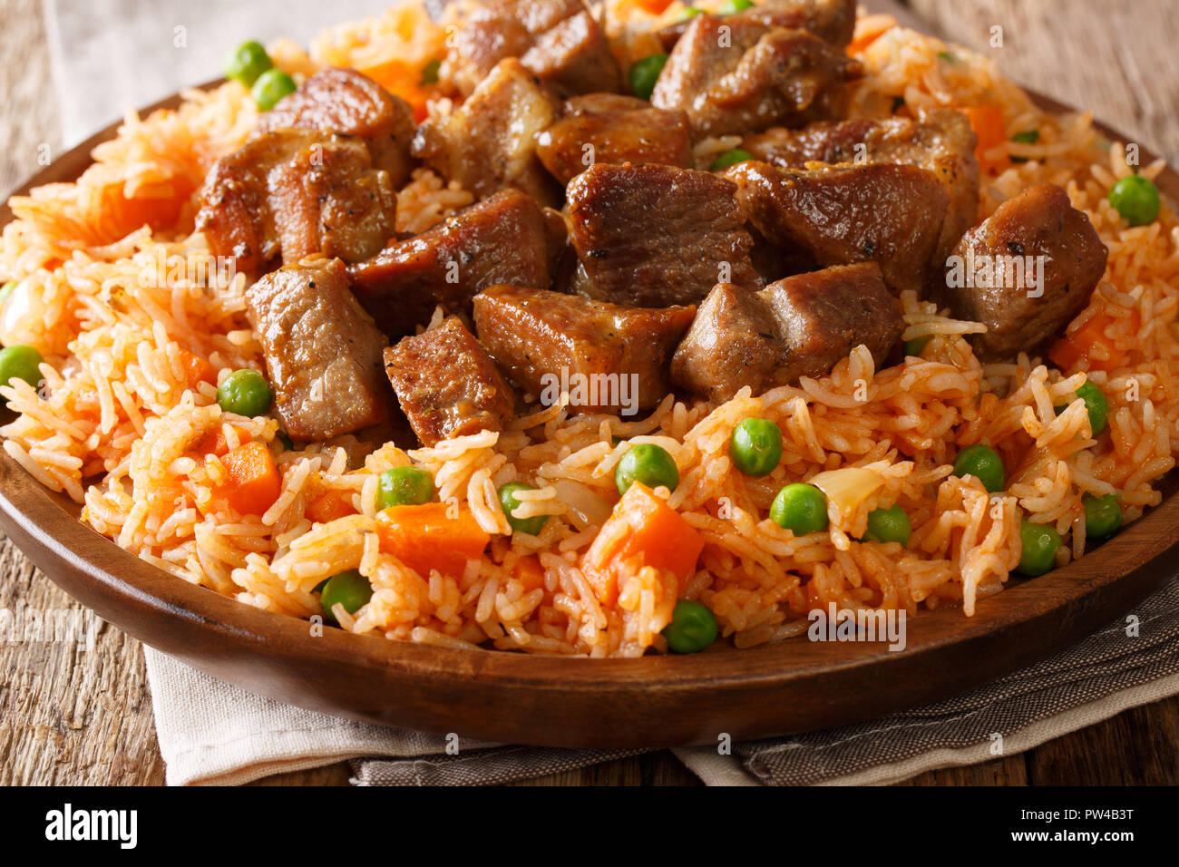 Authentic Mexican rice with green peas and carrots served with spicy pork close-up on a plate on the table. horizontal Stock Photo